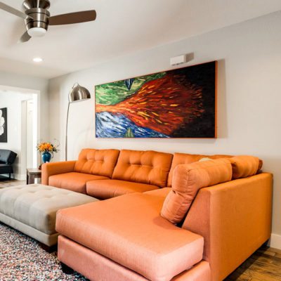 Living room with an orange sofa and a large colorful painting on the wall